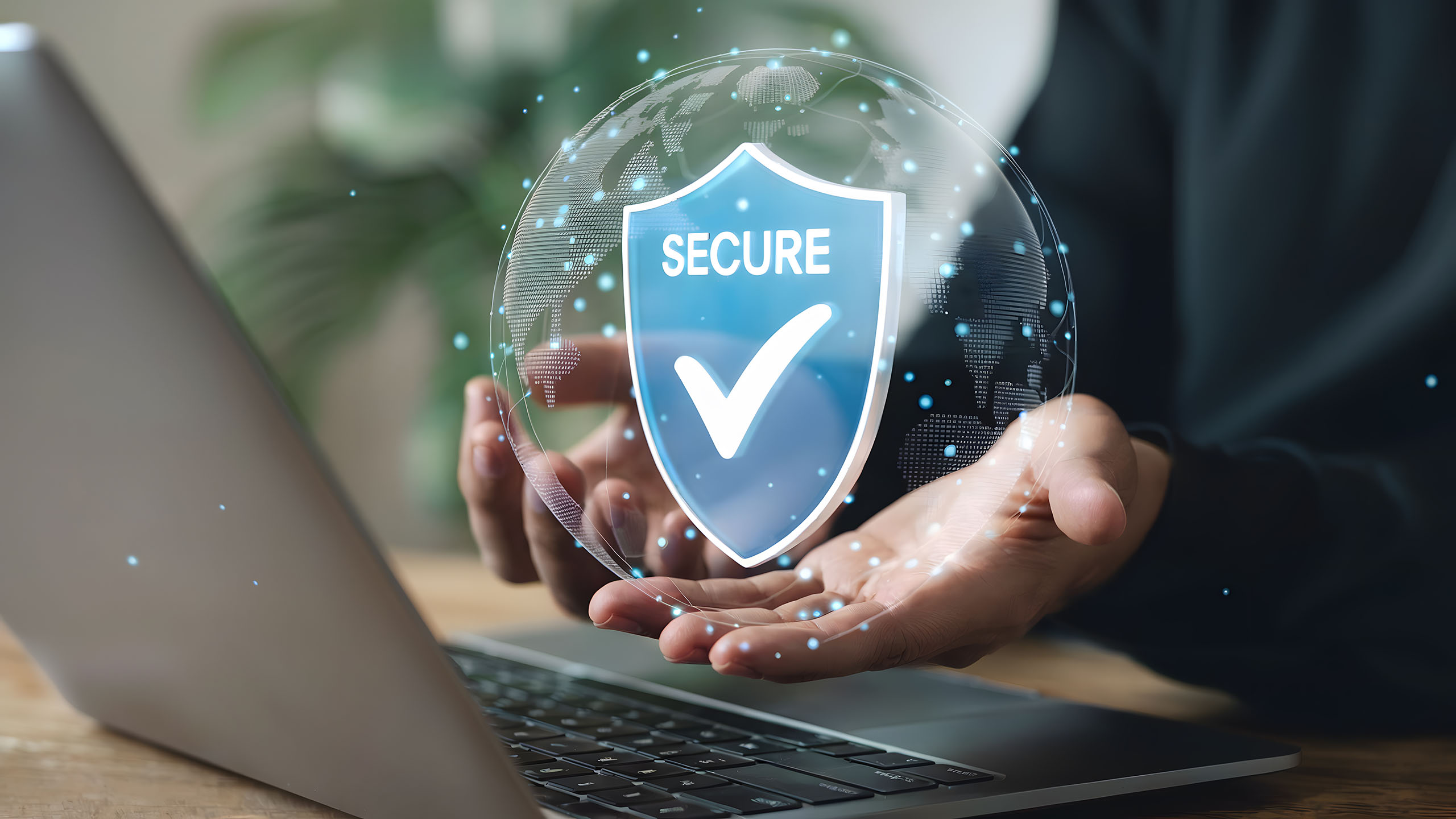 Person holding a digital shield for cybersecurity over a laptop,