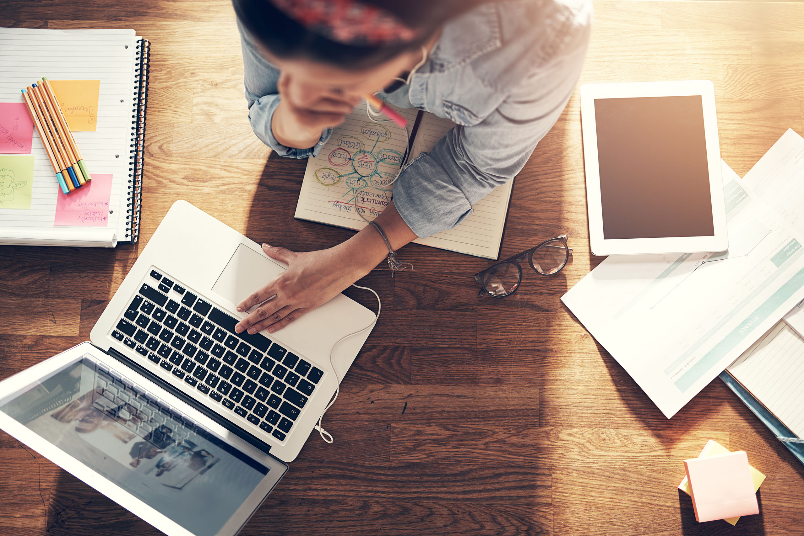 Young female entrepreneur thinking and browsing laptop in office